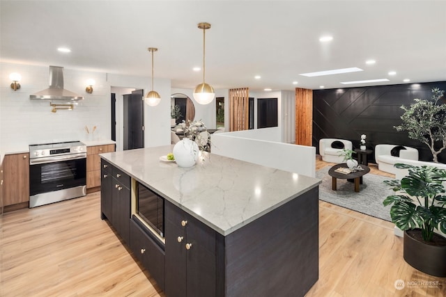 kitchen featuring extractor fan, light stone counters, stainless steel range with electric stovetop, black microwave, and pendant lighting