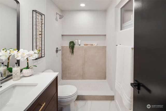 bathroom with vanity, tiled shower, and toilet