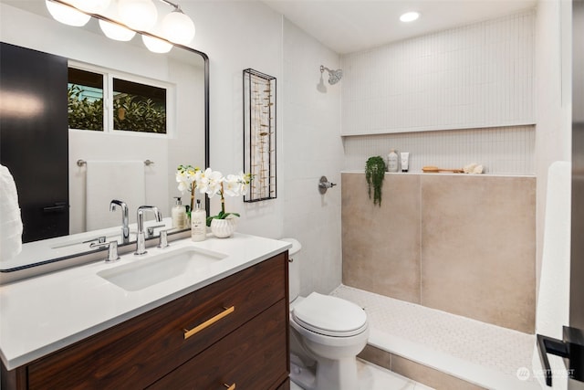 bathroom with vanity, toilet, and a tile shower