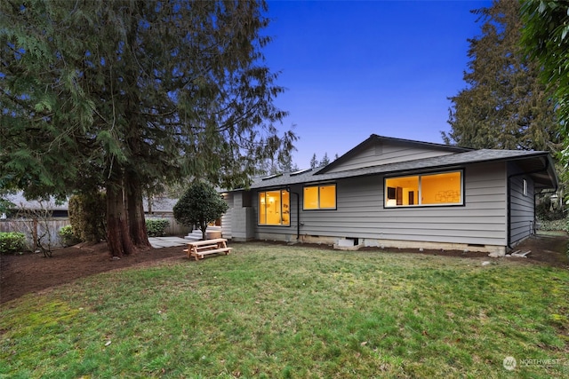 back house at dusk featuring a yard