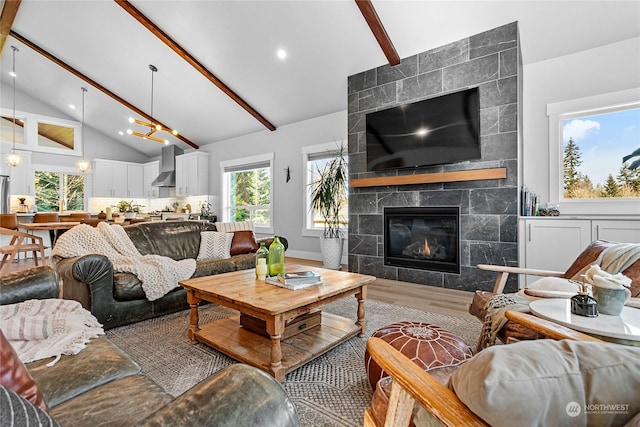 living room featuring a tiled fireplace, hardwood / wood-style floors, high vaulted ceiling, and beamed ceiling