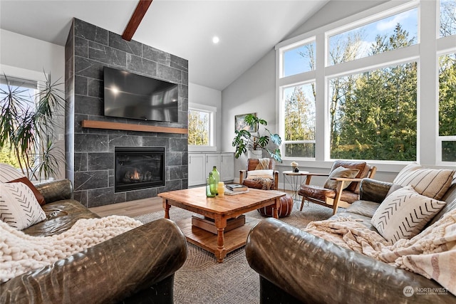 living room featuring hardwood / wood-style flooring, a tile fireplace, and vaulted ceiling with beams