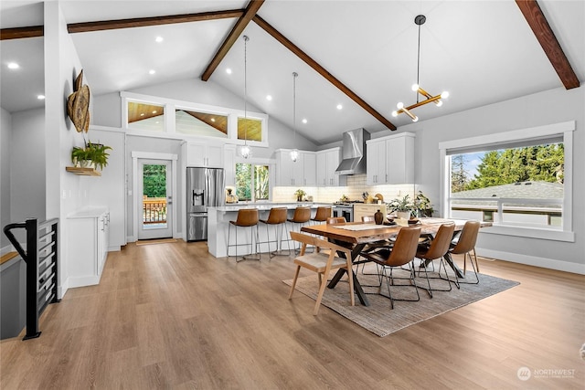 dining room with an inviting chandelier, beam ceiling, and light wood-type flooring