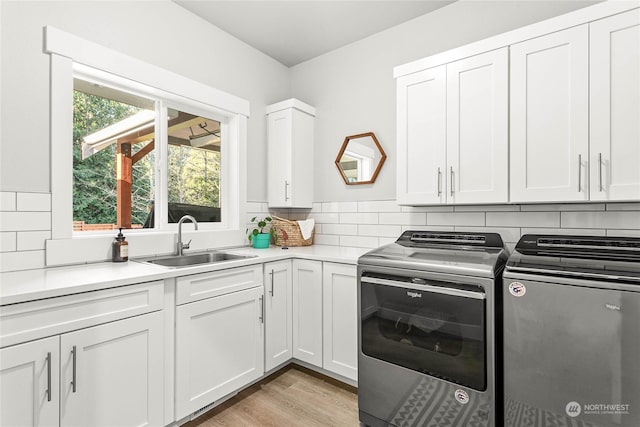 laundry room with cabinets, independent washer and dryer, sink, and light wood-type flooring