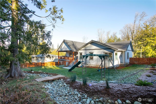 rear view of property featuring a yard and a playground