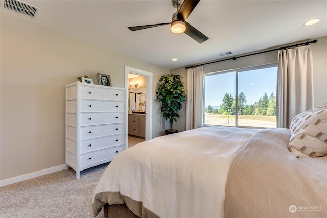 bedroom with ceiling fan, ensuite bath, and light carpet