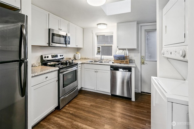 kitchen featuring stacked washer and dryer, sink, dark hardwood / wood-style flooring, stainless steel appliances, and white cabinets