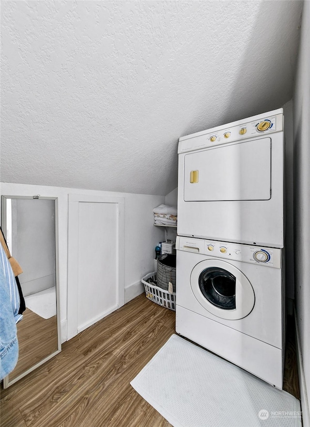 laundry room with stacked washer and clothes dryer, hardwood / wood-style floors, and a textured ceiling