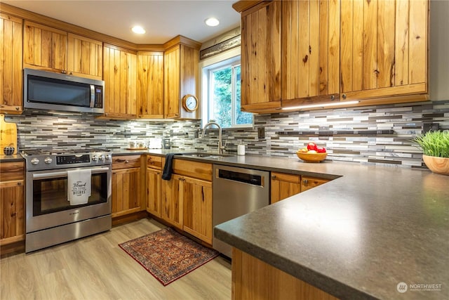 kitchen featuring tasteful backsplash, sink, light hardwood / wood-style flooring, and appliances with stainless steel finishes