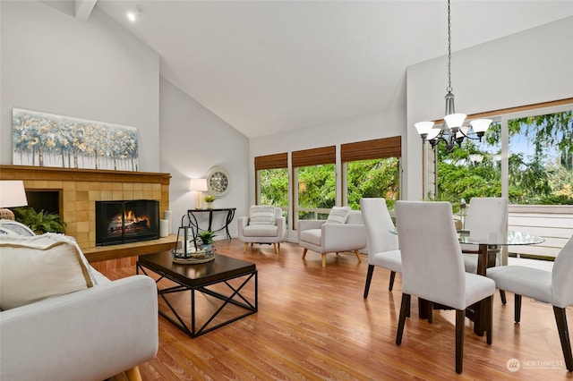 interior space featuring a tiled fireplace, hardwood / wood-style floors, a notable chandelier, and high vaulted ceiling