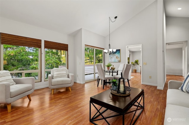 living room featuring high vaulted ceiling, a chandelier, and light wood-type flooring