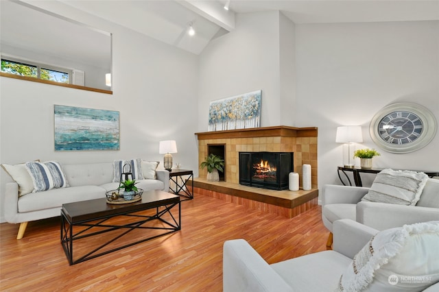 living room with beamed ceiling, a tile fireplace, hardwood / wood-style floors, and high vaulted ceiling