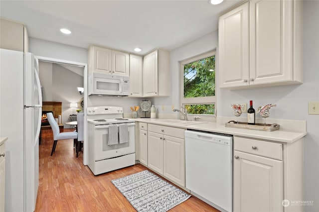 kitchen featuring sink, white cabinets, white appliances, and light hardwood / wood-style floors