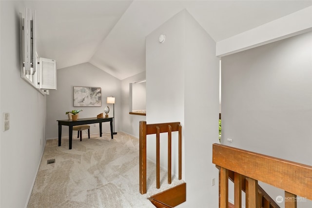 hall with lofted ceiling and light colored carpet