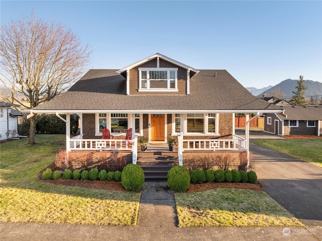 view of front facade featuring a mountain view, covered porch, and a front lawn