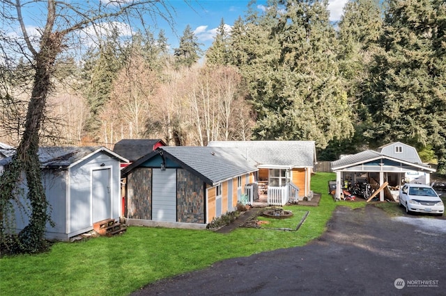 view of front of house with a front yard, an outdoor structure, driveway, and a storage shed