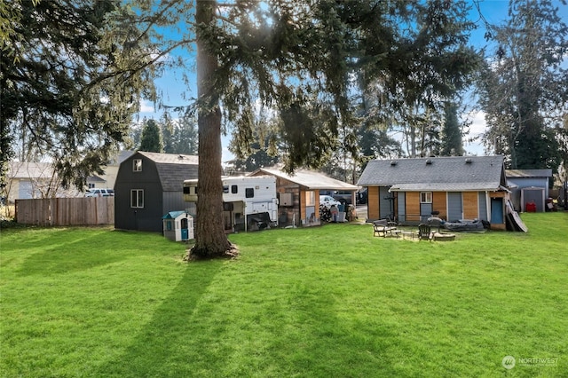 back of property with an outbuilding, a lawn, a storage shed, and fence