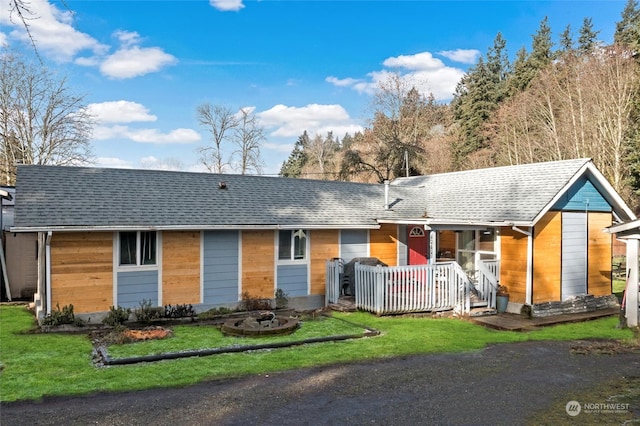 ranch-style home featuring a shingled roof and a front lawn