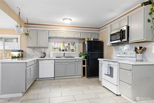 kitchen with white appliances, light countertops, a sink, and gray cabinetry