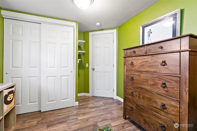 bedroom with a closet, wood finished floors, and baseboards