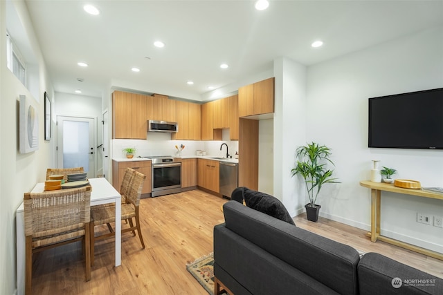 kitchen with stainless steel appliances, sink, and light hardwood / wood-style flooring