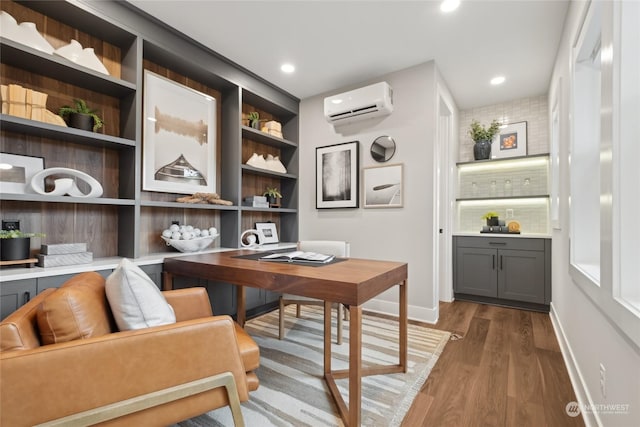 office area with wood-type flooring, a wall unit AC, and built in shelves