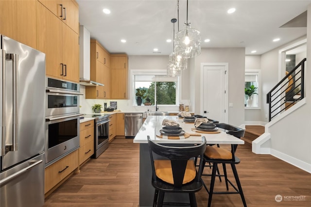 kitchen with a kitchen island, appliances with stainless steel finishes, dark hardwood / wood-style floors, light brown cabinetry, and hanging light fixtures