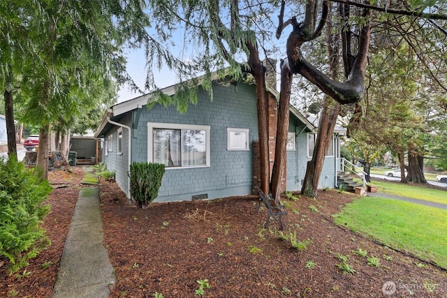 view of side of property with crawl space and a lawn