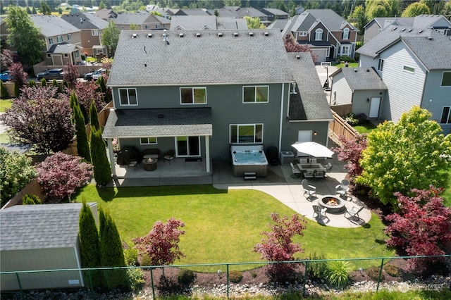 rear view of property with a yard, a fire pit, a storage shed, and a patio