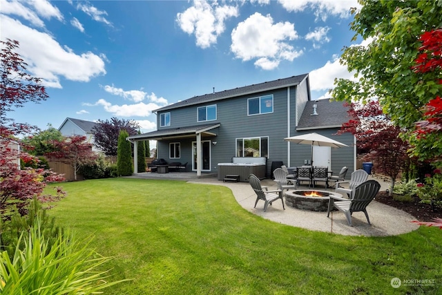 back of house featuring a hot tub, a yard, a patio area, and a fire pit