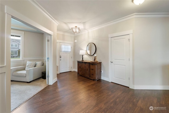 entryway with dark wood-type flooring, ornamental molding, and a chandelier