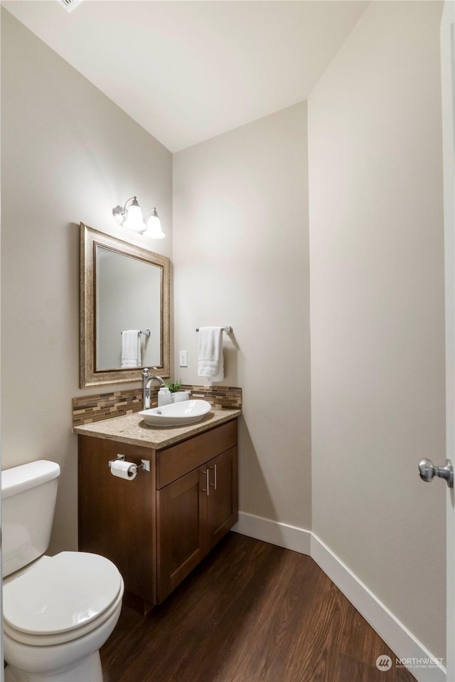 bathroom with hardwood / wood-style flooring, vanity, decorative backsplash, and toilet