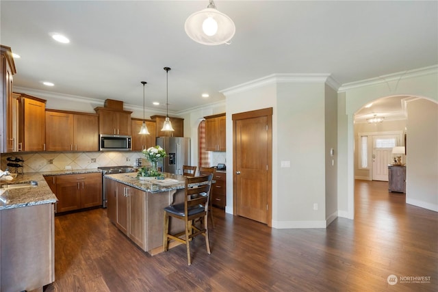 kitchen with stainless steel appliances, a kitchen island, pendant lighting, and stone counters