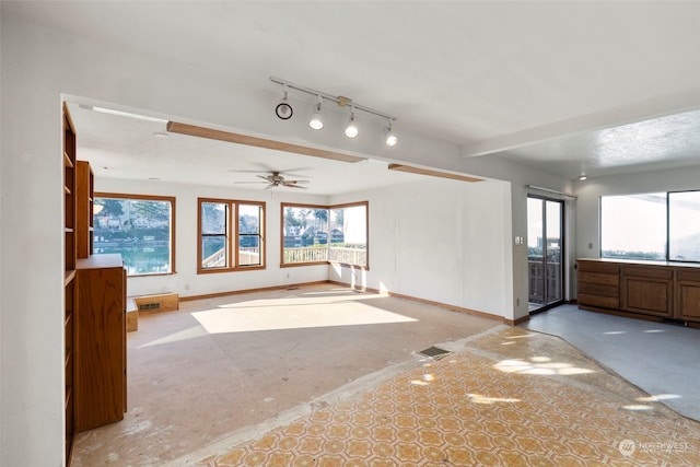 unfurnished living room featuring ceiling fan and rail lighting