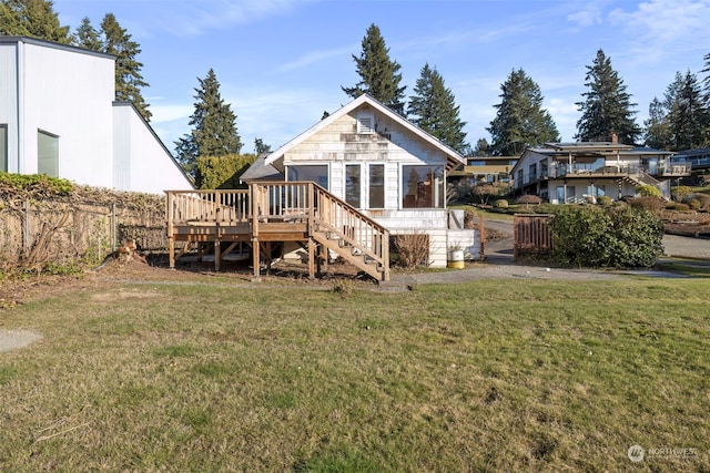 back of property with a wooden deck and a lawn