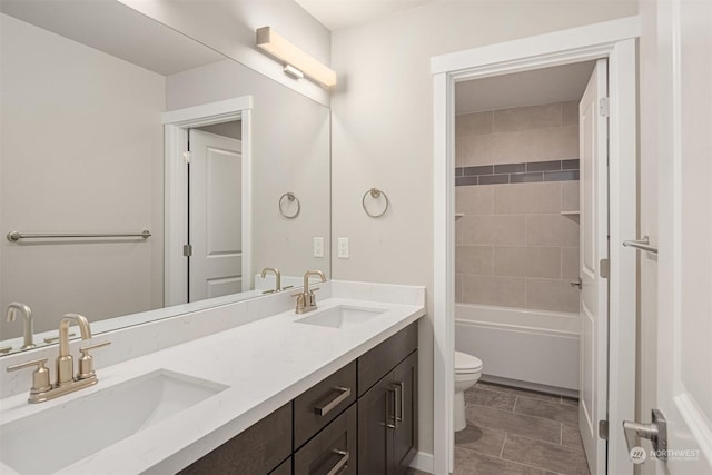 full bath with toilet, shower / bath combination, double vanity, and a sink