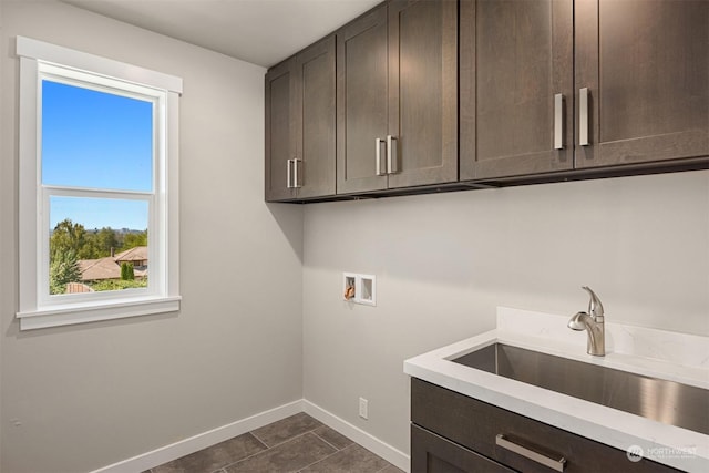 laundry room with dark tile patterned floors, washer hookup, a sink, baseboards, and cabinet space