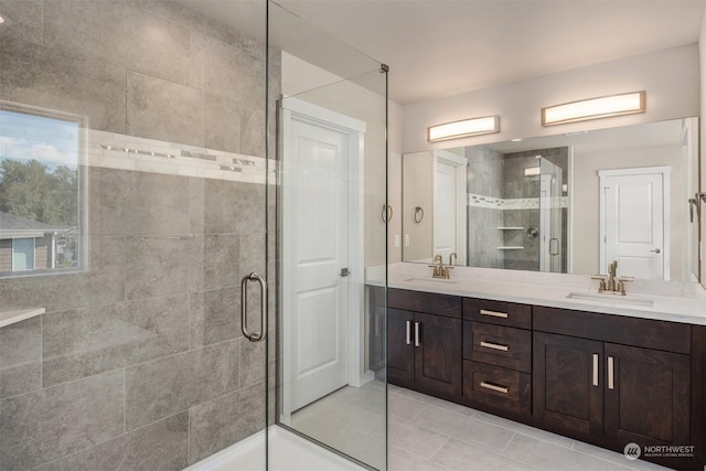 bathroom with double vanity, a stall shower, a sink, and tile patterned floors