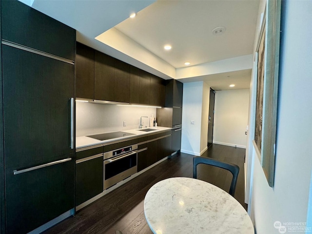 kitchen featuring dark wood-type flooring, oven, paneled refrigerator, black electric stovetop, and a raised ceiling