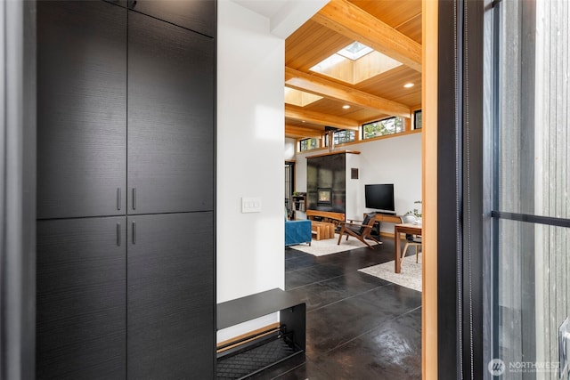 interior space with concrete flooring, beamed ceiling, a skylight, and wooden ceiling