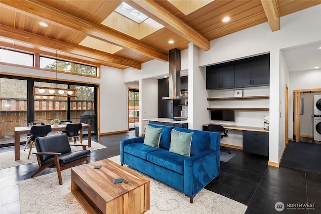 living room featuring a skylight, stacked washer / dryer, built in study area, wood ceiling, and beam ceiling