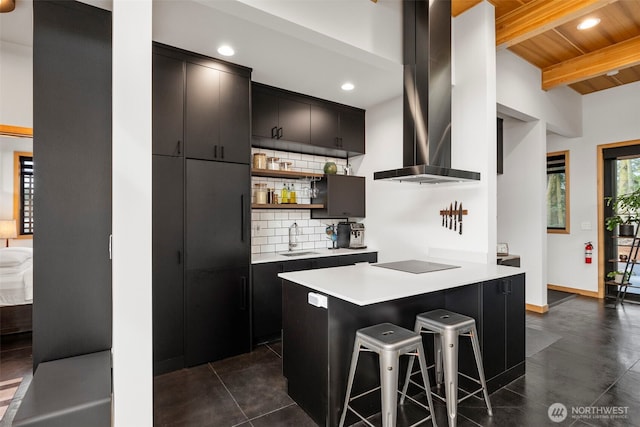 kitchen featuring backsplash, a sink, wall chimney range hood, beamed ceiling, and black electric cooktop