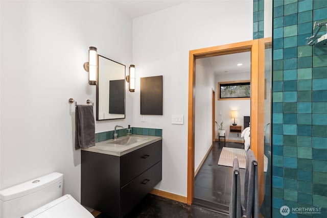 full bath featuring baseboards, toilet, ensuite bathroom, a tile shower, and vanity