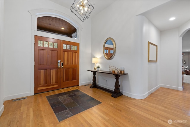 entrance foyer with an inviting chandelier, hardwood / wood-style floors, and a towering ceiling