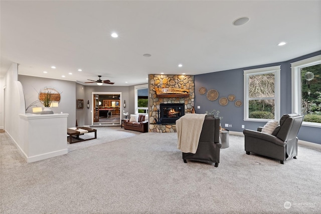 living room featuring ceiling fan, a fireplace, and light carpet