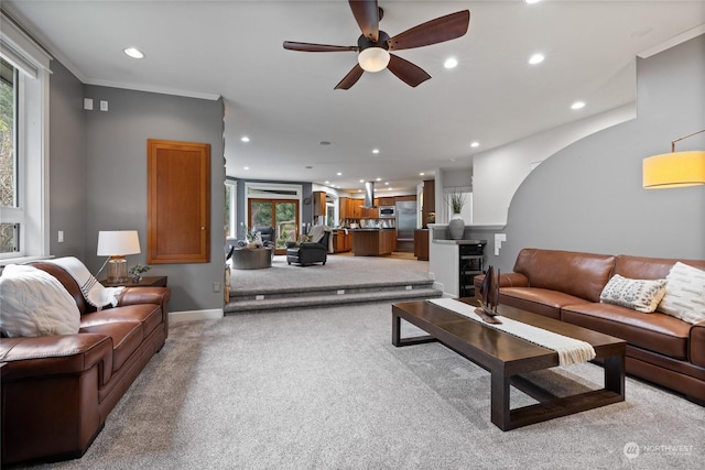 carpeted living room with crown molding and ceiling fan