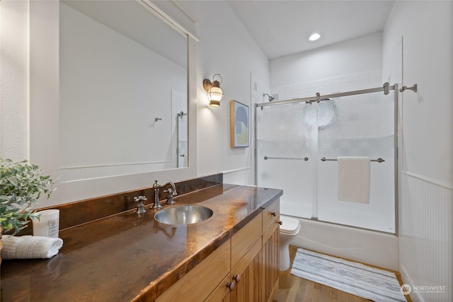 full bathroom with vanity, wood-type flooring, bath / shower combo with glass door, and toilet