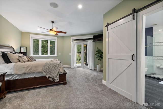 carpeted bedroom with access to exterior, ensuite bath, a barn door, and ceiling fan