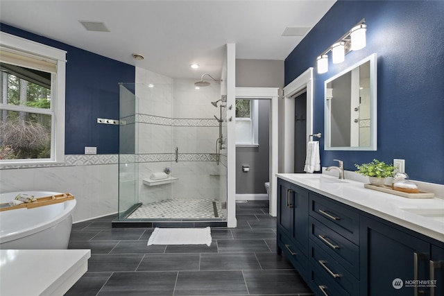 full bathroom featuring vanity, toilet, independent shower and bath, and tile walls