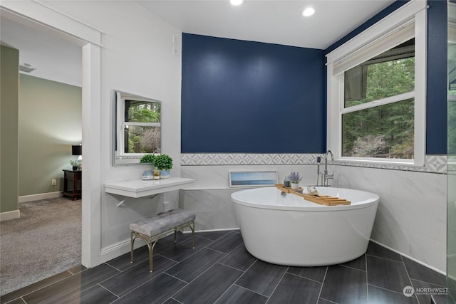 bathroom featuring tile walls and a tub to relax in